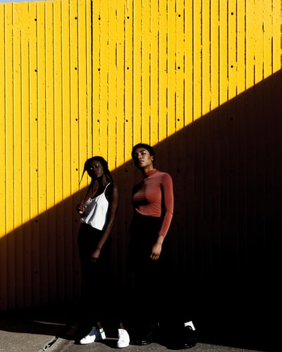 两个女人站在黄色的墙前